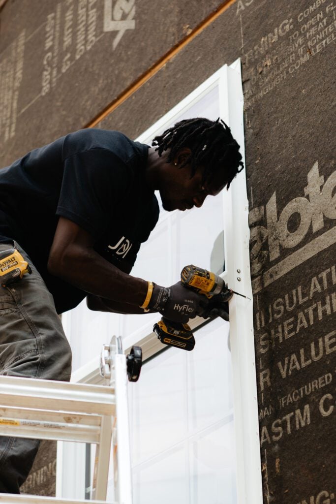 A man is installing a window, showcasing JDI Windows' craftsmanship and attention to detail.