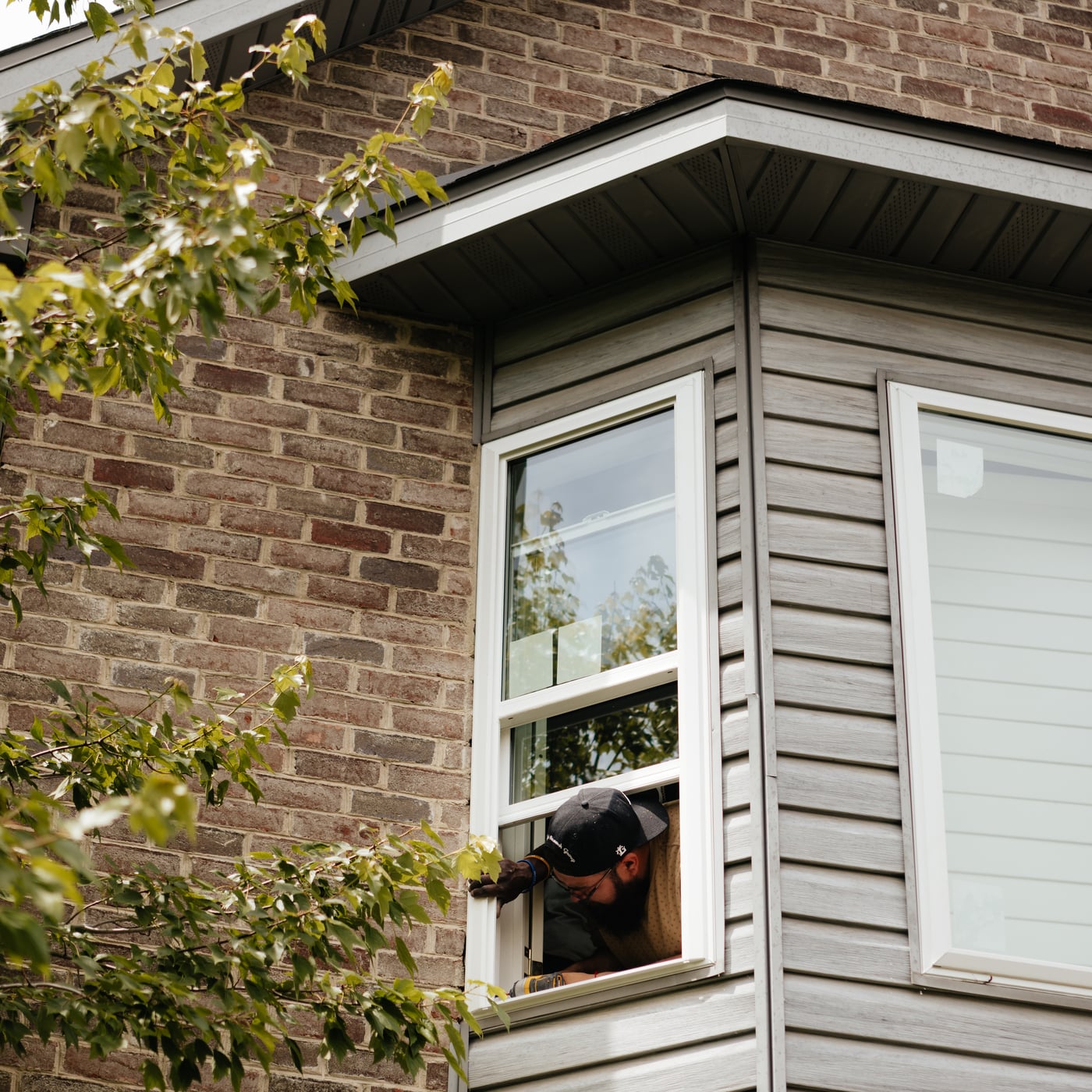 A man gazes out of a house window, showcasing JDI Windows' design and craftsmanship.