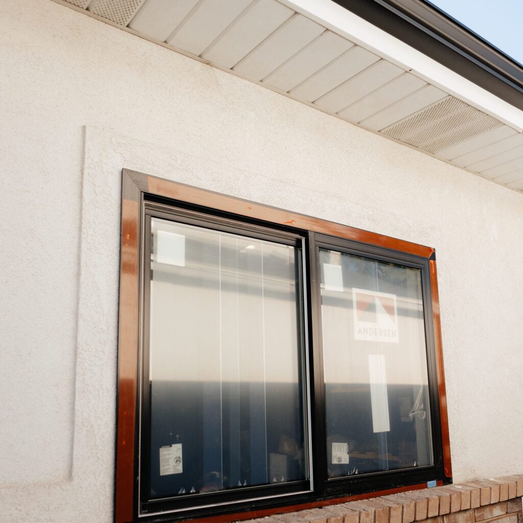 A brown-framed window featuring a black pane, branded with the JDI Windows logo.