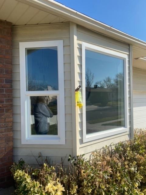 A man sitting in a house window, showcasing JDI Windows' design and functionality.