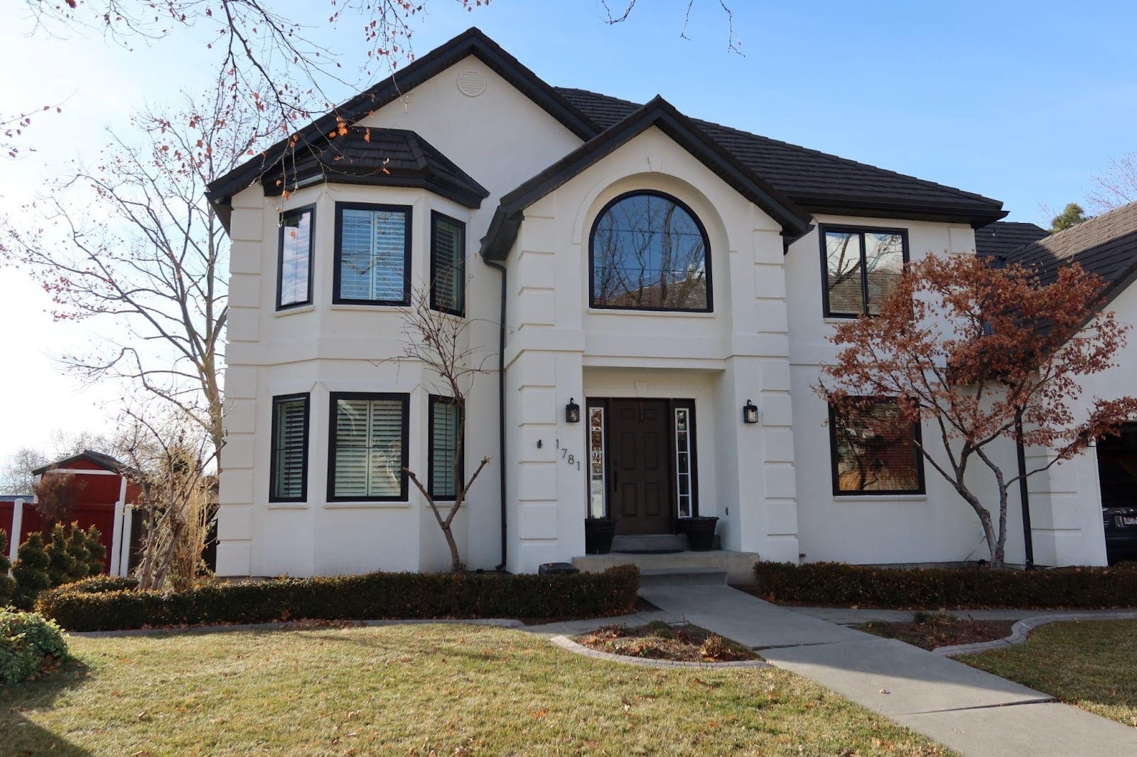 A large white house featuring black trim and windows set against a clear blue sky