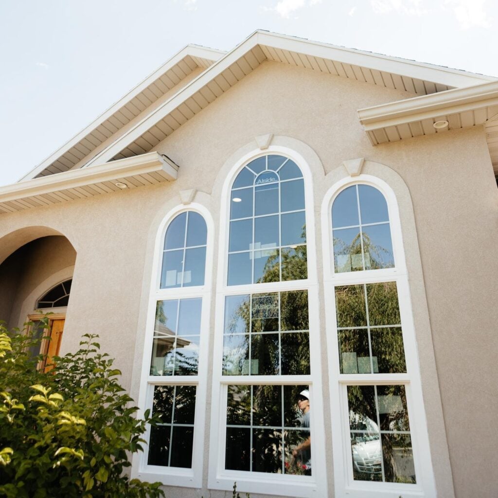 A house featuring a large window framed with white trim showcasing a bright and inviting exterior