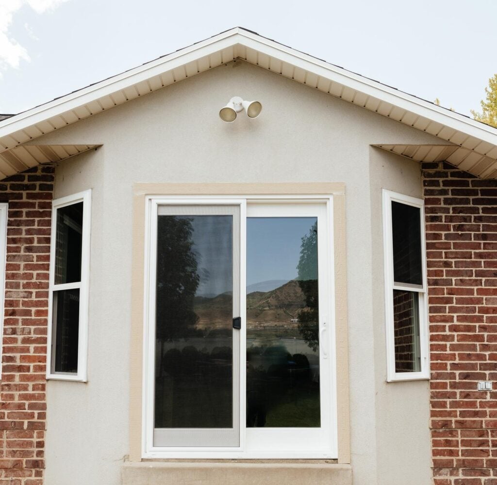 A white door with a window surrounded by a sturdy brick wall emphasizing a traditional building style