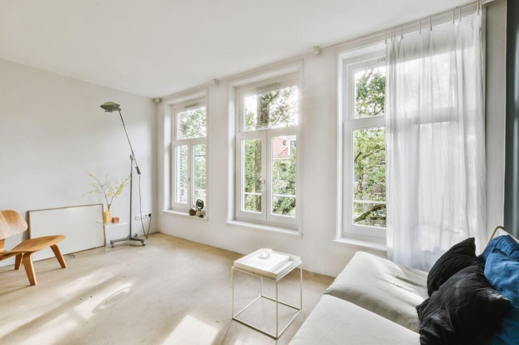 A spacious living room with white walls and windows allowing natural light to fill the space