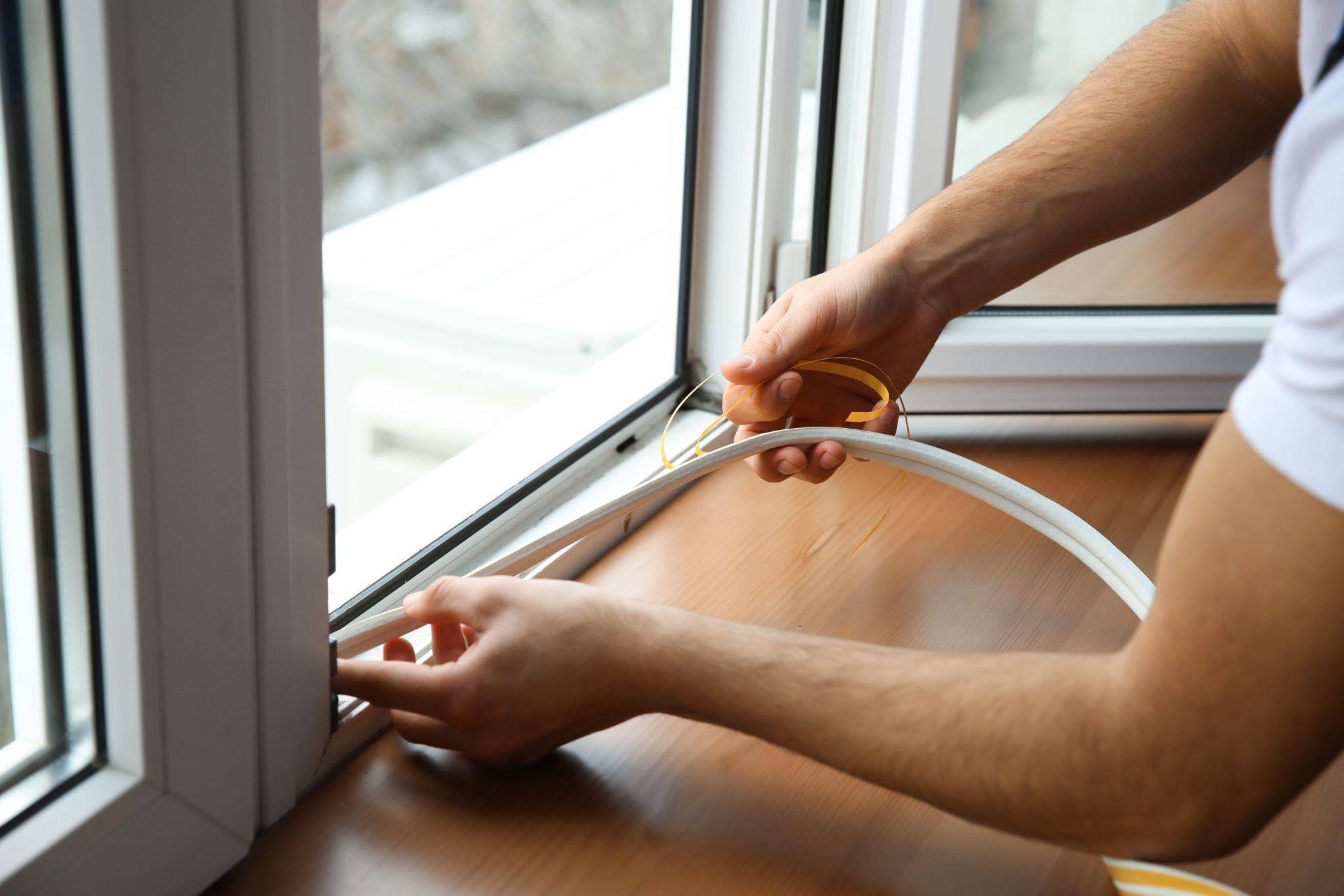 A man is seen fixing a window with a white cord showcasing practical skills in home repair